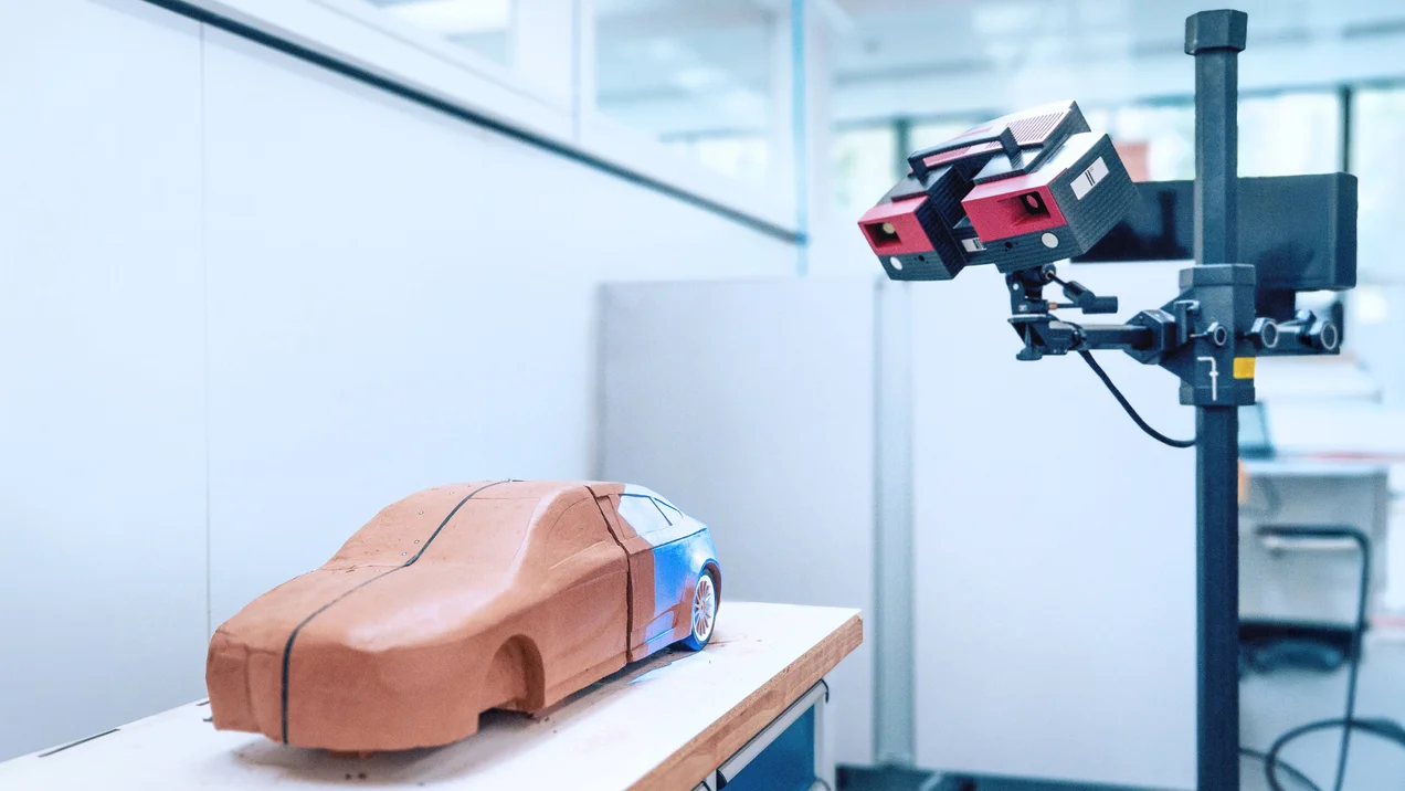 Ein roter 3D-Scanner scannt ein Modellauto