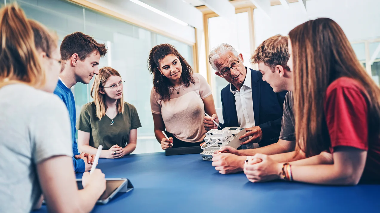Hands-on im Smartgrid-Labor: Professor demonstriert einer Gruppe von Studierenden die Funktionsweise eines technischen Bauteils.