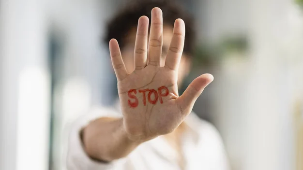 Person streckt ihre Handfläche zur Kamera. In der Hand steht in roten Buchstaben "STOP".