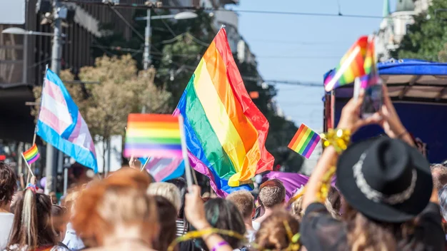 A crowd waving a rainbow flag is demonstrating for equal rights on the street