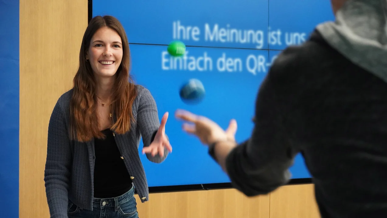 Zwei Personen werfen sich als Koordinationsübung zwei Bälle zu.