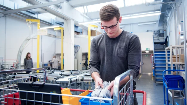 Ein Student sortiert mit Hilfe einer Kommissionierungs-Brille Lagergegenstände ein.