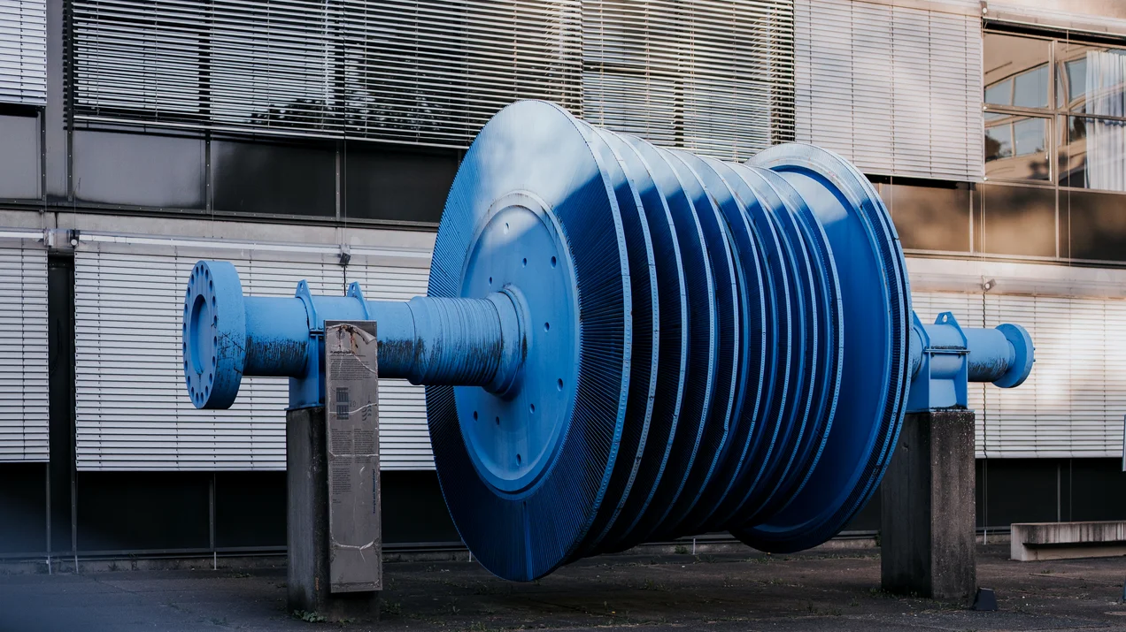 Blaue Gasturbine als technisches Exponat vor einem Glasgebäude am Campus Prittwitzstraße der Technischen Hochschule Ulm.