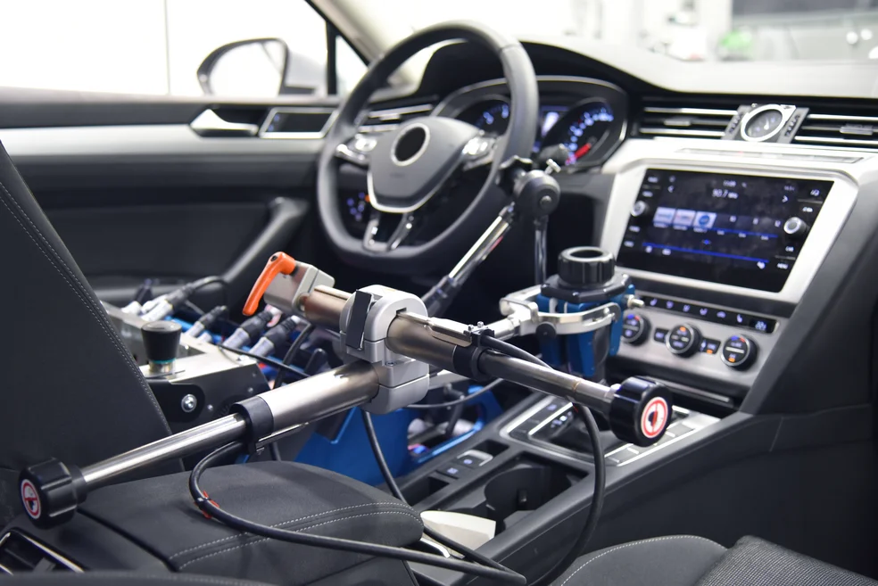 Innenaufnahme eines selbstfahrenden Autos. Ein Roboterarm steuert die Gangschaltung.