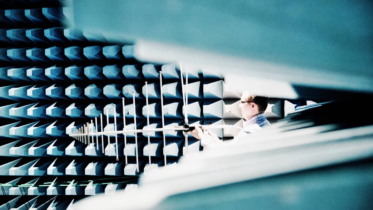 Measurement in the absorber chamber, a room equipped with RF absorbers. A person is working on an antenna.