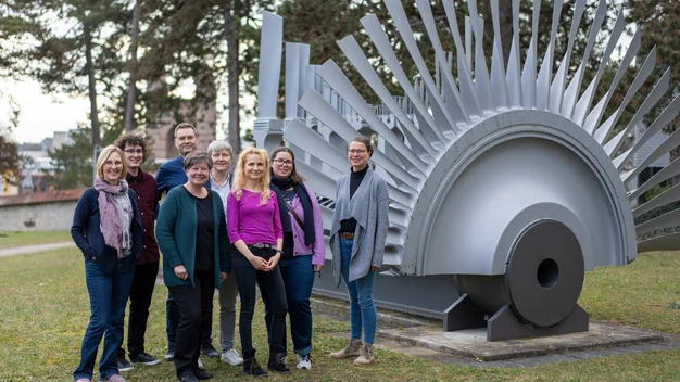 cosh-Regioteam: Links sind die Personen zu sehen, rechts eine Turbine.
