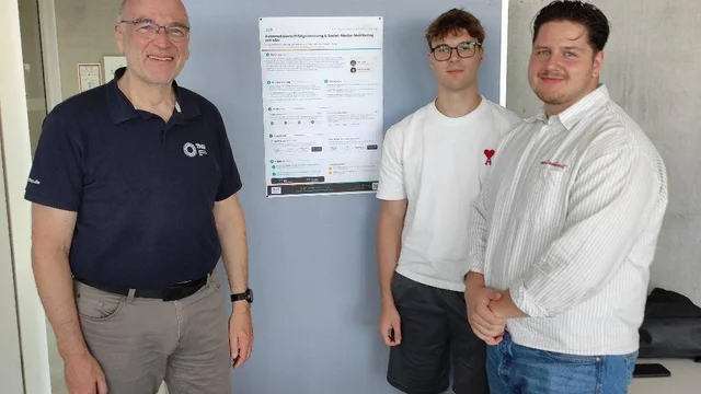 Zwei Studenten und ein Dozent stehen nach der Präsentation ihres Praxisprojekts im Studiengang Wirtschaftsinformatik gemeinsam in einem Büro vor einem Präsentationsposter.