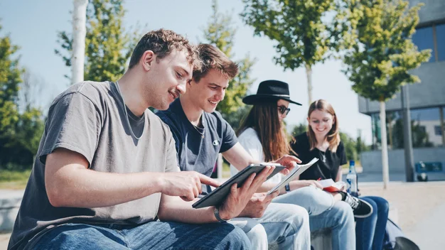 Teamwork im Freien: Eine Gruppe schaut fokussiert auf ein Tablet. Fokus auf digitale Zusammenarbeit und Gemeinschaft.