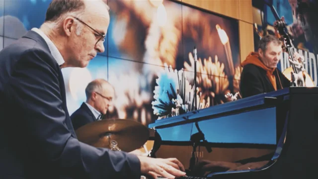 Zwei Personen musizieren vor einem festlich geschmückten Hintergrund für die Weihnachtsgrüße 2025.