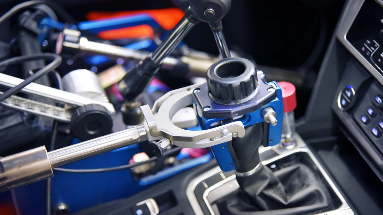 Close-up of a car's gearshift. A robotic arm controls it.