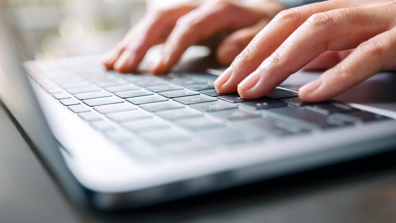 a woman working and typing on laptop computer on the table