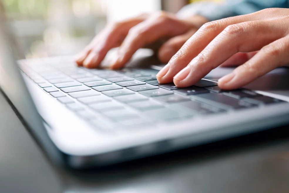 a woman working and typing on laptop computer on the table