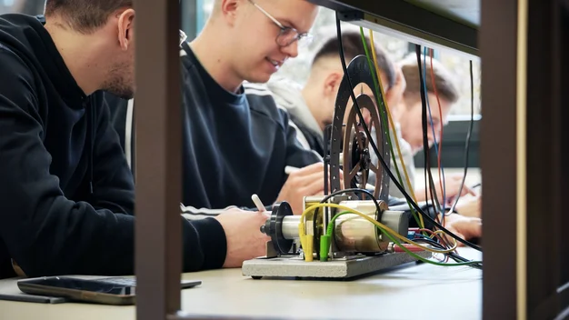 Studierende sitzen hinter einem Rad beim Versuch im Physiklabor