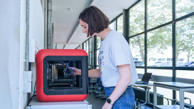 Studentin holt ihr fertig gedrucktes 3D-Modell aus dem 3D-Drucker