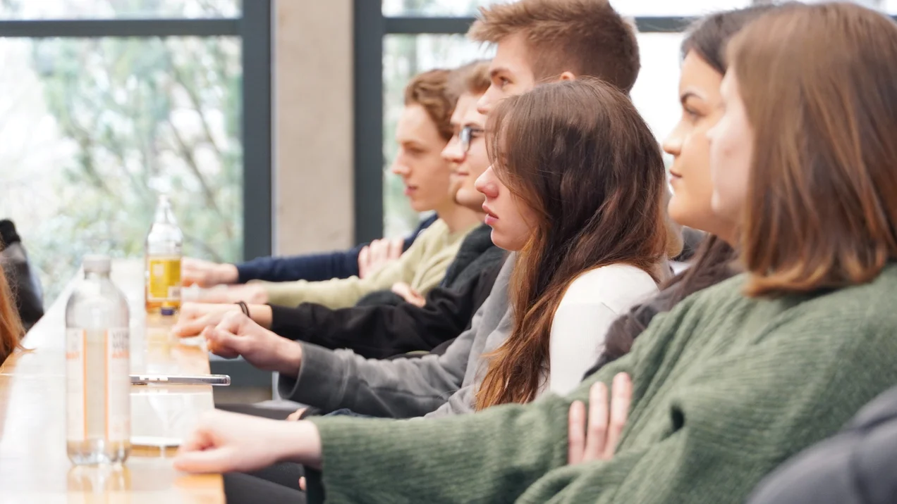 Studierende in einem hellen Vorlesungsraum klatschen Beifall.