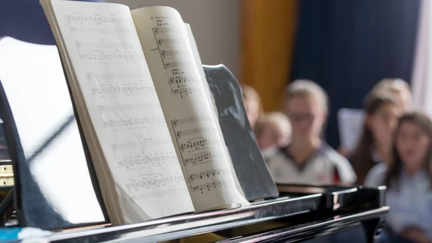 Detailaufnahme Klavier mit Noten und Chor im Hintergrund