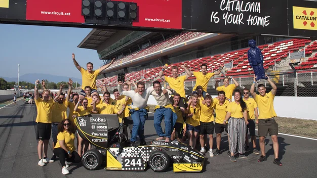 Auf diesem Bild sind mehrere Personen des Einstein Motorsports Team sichtbar. Sie stehen um ihren selbstgebauten Rennwagen und jubeln.