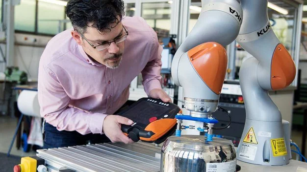 Person programmiert einen KUKA-Roboter im Labor.